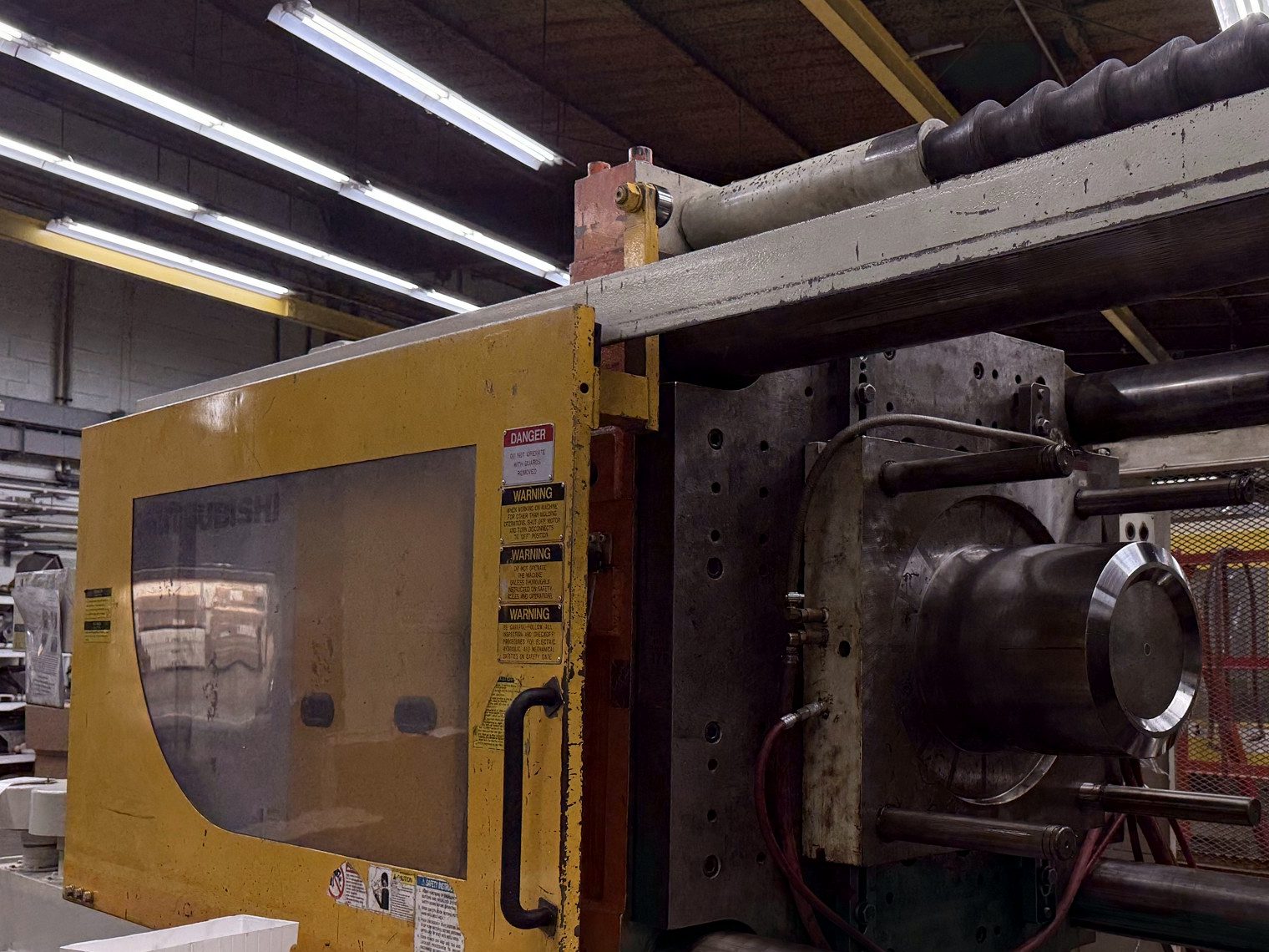 The open platen of a yellow Mitsubishi machine, with the mold area exposed