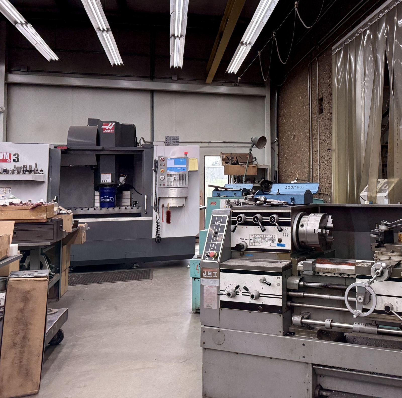 A Haas vertical machining center behind an engine lathe in the tool room